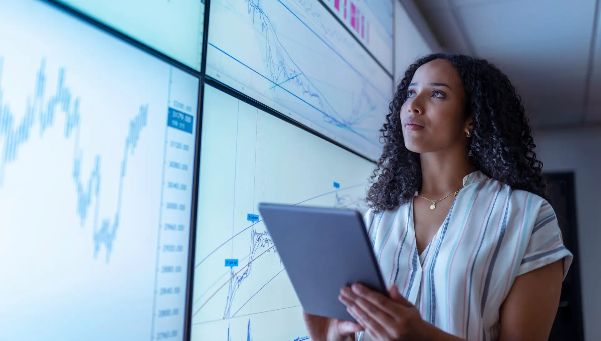 Women working with big data next to large screens of graphs and data analysis